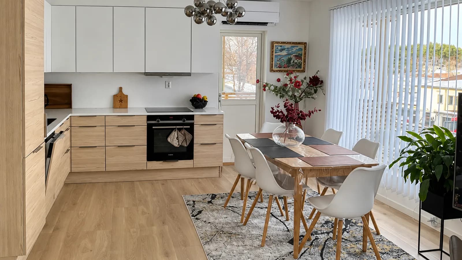 Åpent kjøkken og spisestue med spisebord for seks i en møblert bolig